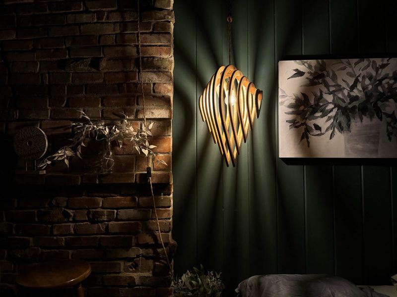 Bamboo pendant light glowing against a dark green wall