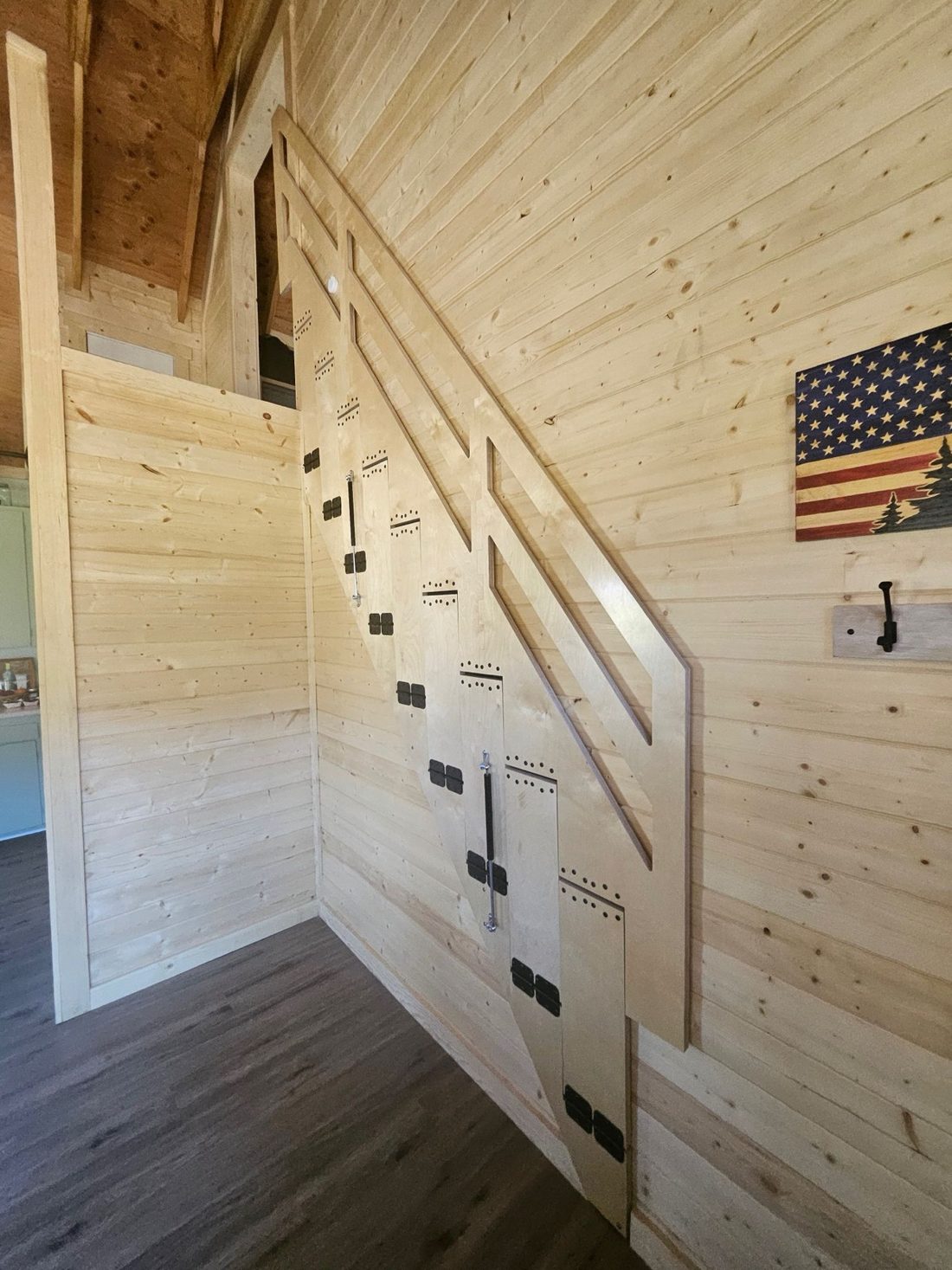 The same stair folded up flat against the pine wall, leaving the floor clear